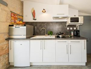 eine Küche mit weißen Schränken und einem Waschbecken in der Unterkunft Gîte du timbre in Clion