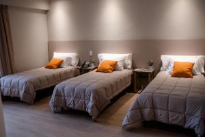 two beds with orange pillows in a room at Gran Hotel Dakar in Mendoza