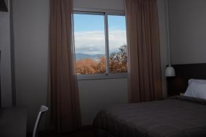 a bedroom with a bed and a window with a view at Gran Hotel Dakar in Mendoza