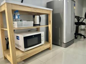 a microwave on a shelf next to a refrigerator at PrivateRayong in Rayong