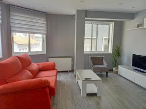 sala de estar con sofá rojo y TV en O Abeiro do Eume, en Puentedeume
