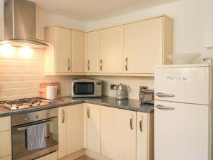 a kitchen with white cabinets and a white refrigerator at Hope Cottage in Buckfastleigh +9 photos