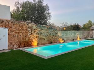 - une piscine en face d'un mur en pierre dans l'établissement Can Roig, à Ses Salines