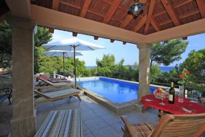 a pool with a table and chairs and an umbrella at Villa Nova in Vela Luka