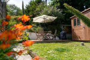 a table and chair with an umbrella in a garden at Curlew Cottage in Uny Lelant