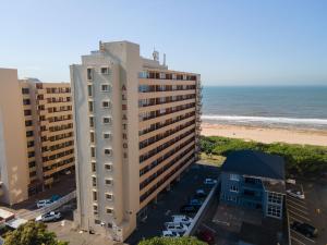 a tall white building next to the beach at Albetros 904 in Amanzimtoti