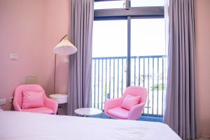 a room with two pink chairs and a large window at 看見花蓮民宿See Hualien Homestay in Hualien City