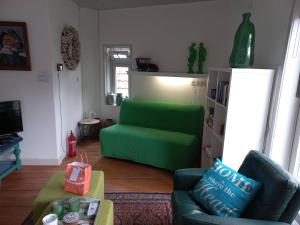 een woonkamer met een groene bank en een stoel bij Knus vertoeven in een historisch pand in Grou. in Grou