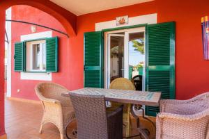 ein Tisch und Stühle auf einer Terrasse mit grünen Fensterläden in der Unterkunft Villa Malena in Llucmajor