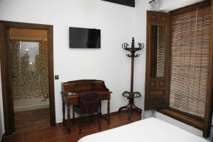 a bedroom with a desk and a bed with a television at HABITACIONES LAS TERMAS in Guadix