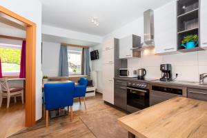 a kitchen with a table and blue chairs in a room at Appartements am Edthof in Eben im Pongau