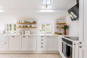 eine weiße Küche mit weißen Schränken und einer Spüle in der Unterkunft Honeysuckle Cottage in Wareham + 21 Fotos