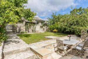 eine Terrasse mit Tisch und Stühlen in einem Hof in der Unterkunft Honeysuckle Cottage in Wareham