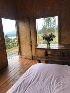 Un dormitorio con una cama y una mesa con un jarrón de flores en La Casa de las Estrellas en Suesca