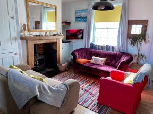 sala de estar con 2 sofás morados y chimenea en Coastguards Beach House, en Camber