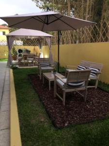 een groep stoelen en een paraplu in een tuin bij Casa de Praia Guest House in Labruge