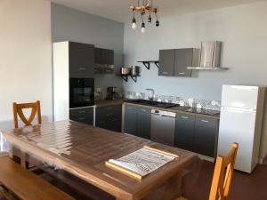 uma cozinha com uma mesa de madeira e um frigorífico em appartement 12 couchages proche piste ski et de randonnées du lioran em Le Lioran