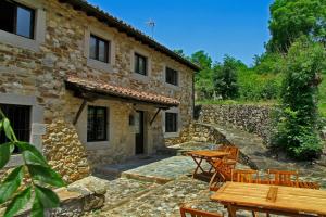 an external view of a stone house with a table and chairs at La Posada de la Xana in Llanuces