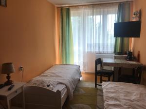 a bedroom with two beds and a desk and a window at Pokoje gościnne U Wandy in Ostrowo