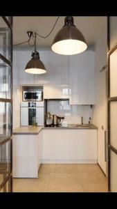a kitchen with white cabinets and two lights at Central Apartment on Rynok sk. in Lviv