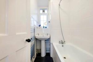 a white bathroom with a sink and a bath tub at Fabulous 2 Bedroom Apartment in London Bridge in London