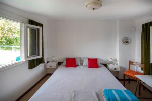 a bedroom with a white bed with red pillows at Anni's cozy apartments 50m from the beach in Agia Triada