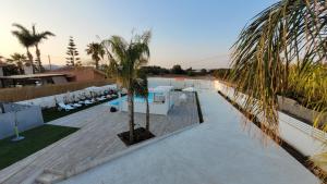 a pool with chairs and a palm tree next to a building at Amurusu Residence in Punta Secca