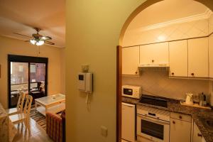 une cuisine avec des placards blancs et un salon dans l'établissement Apartamento playa de Samil, à Vigo