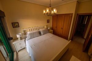 - une chambre dotée d'un lit avec des draps blancs et un lustre dans l'établissement Apartamento playa de Samil, à Vigo
