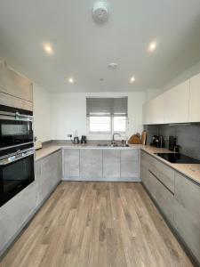 Il comprend une grande cuisine avec des placards blancs et du parquet. dans l'établissement Modern Penthouse flat with Free Indoor Parking, à Londres