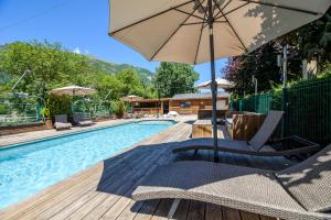 una piscina con dos sillas y una sombrilla en Hôtel Neste de Jade, en Saint-Lary-Soulan