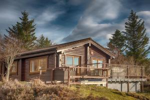 a wooden house with a large deck on a hill at Muir-lan cabin in Lochinver