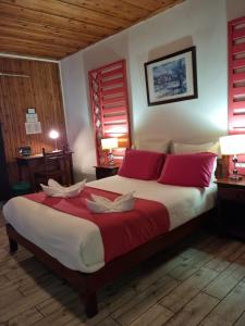 a bedroom with a large bed with red and white pillows at Hotel Des Neiges in Cilaos