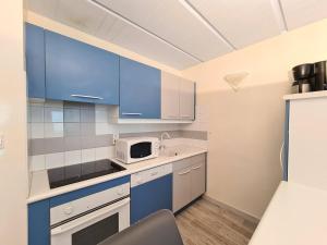 een keuken met blauwe kasten en een magnetron bij Appartement Flaine, 2 pièces, 6 personnes - FR-1-425-47 in Flaine