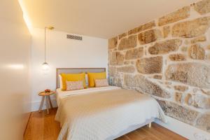een slaapkamer met een stenen muur en een bed met gele kussens bij D&S - Lazaros Apartments in Porto