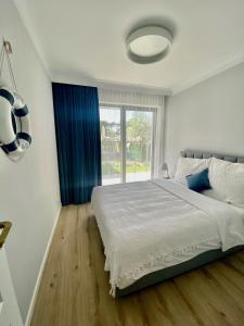 une chambre blanche avec un grand lit et une fenêtre dans l'établissement Rezydencja Niechorze 108 Prestige by The Beach z Basenem i SPA, à Niechorze