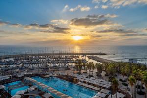 un complejo con piscina y playa al atardecer en Leonardo Gordon Beach, en Tel Aviv