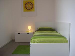 a bedroom with a bed with a green blanket and a lamp at Ferienwohnungen Jordanshof in Xanten