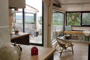 een keuken met een tafel en een groot glazen raam bij Appartement sur les toits, très jolie vue Provence in Gréoux-les-Bains