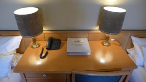 een bureau met twee lampen en een telefoon erop bij Central-Hotel Greiveldinger in Perl