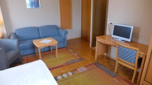 a living room with a blue couch and a desk with a computer at Central-Hotel Greiveldinger in Perl