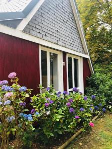a red house with flowers in front of it at Chalet en Normandie au coeur du pays d'Auge in Le Pin