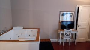 a bathroom with a tub and a desk with a television at Acquadellarte B&B in Catania