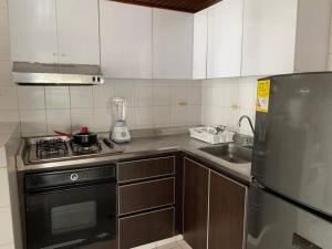 a kitchen with a stove and a sink and a refrigerator at Apartamento en el Laguito - Cartagena cerca al mar in Cartagena de Indias