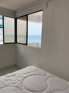 a white bedroom with a bed and a window at Apartamento en el Laguito - Cartagena cerca al mar in Cartagena de Indias