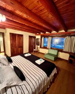 a bedroom with a large bed and a green chair at Trawen Hostal Boutique in Caviahue
