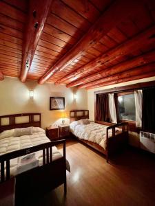 a bedroom with two beds and a wooden ceiling at Trawen Hostal Boutique in Caviahue