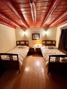 1 dormitorio con 2 camas y techo de madera en Trawen Hostal Boutique en Caviahue