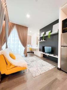 ein Wohnzimmer mit einem gelben Sofa und einem TV in der Unterkunft Aurora Vista Homestay Bangi at Vista Bangi With WIFI NETFLIX GYM SAUNA COWAY SWIMMING POOL-RIVER VIEW in Kajang