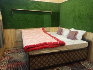 Bett in einem Zimmer mit grüner Wand in der Unterkunft Midway Home stay in Jibhi